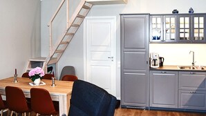 A kitchen with a wooden staircase, grey cabinets, a dining table with chairs, and a small window. - 4 Star Holiday Home in Vatne (Ålesund)