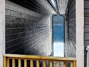 Un pasillo de madera que conduce a un amplio ventanal con vista a una masa de agua.