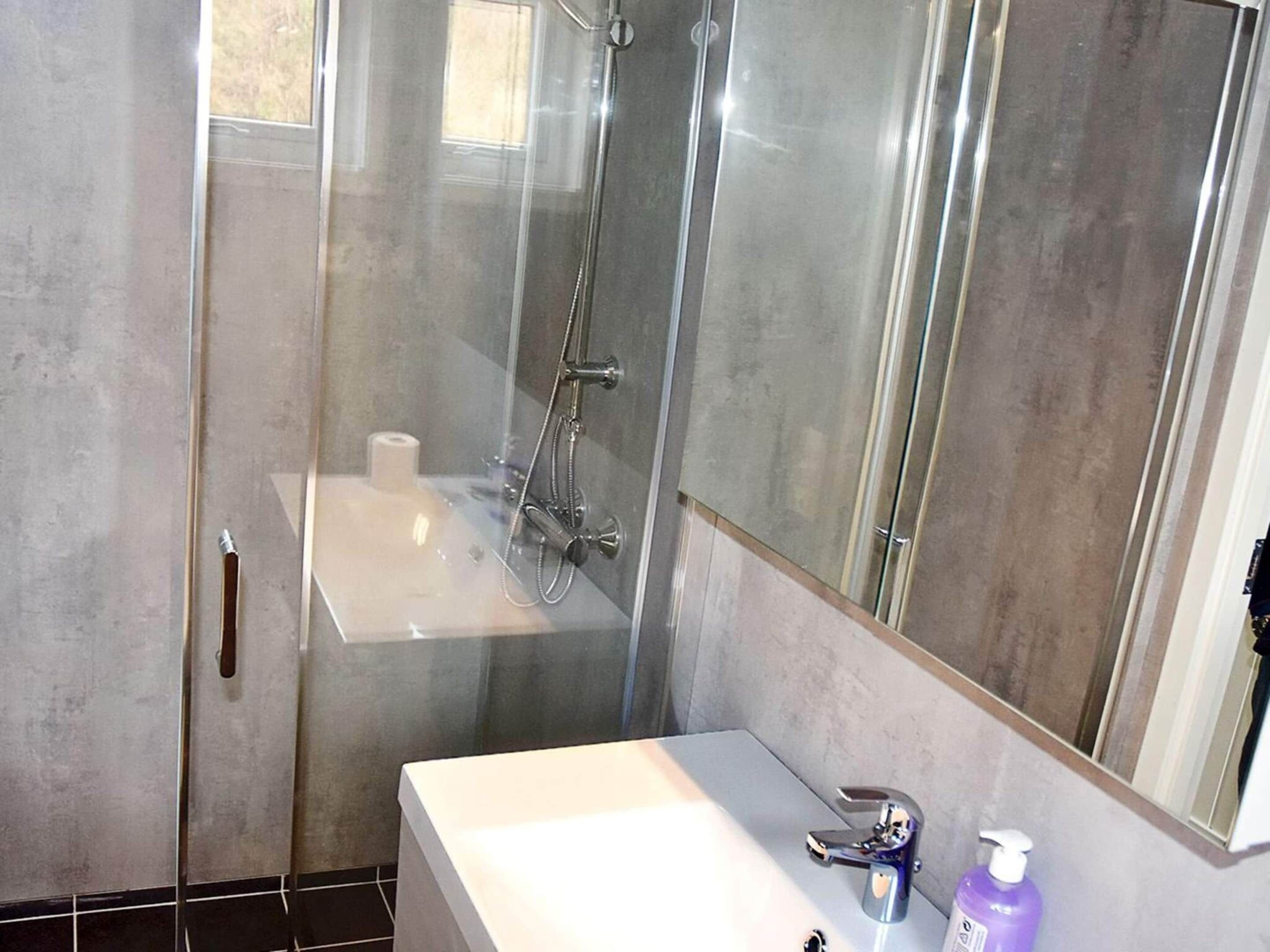 Een moderne badkamer met een douchecabine van glas, een wit wastafelmeubel en een spiegel.