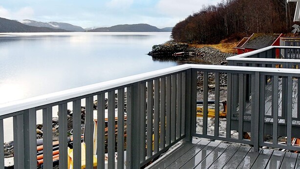 A wooden deck overlooking a calm lake with mountains in the distance. - 4 Star Holiday Home in Vatne (Ålesund)
