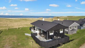 En rad moderna stugor med en terrass, en möblerad uteplats under tak och utsikt över havet.