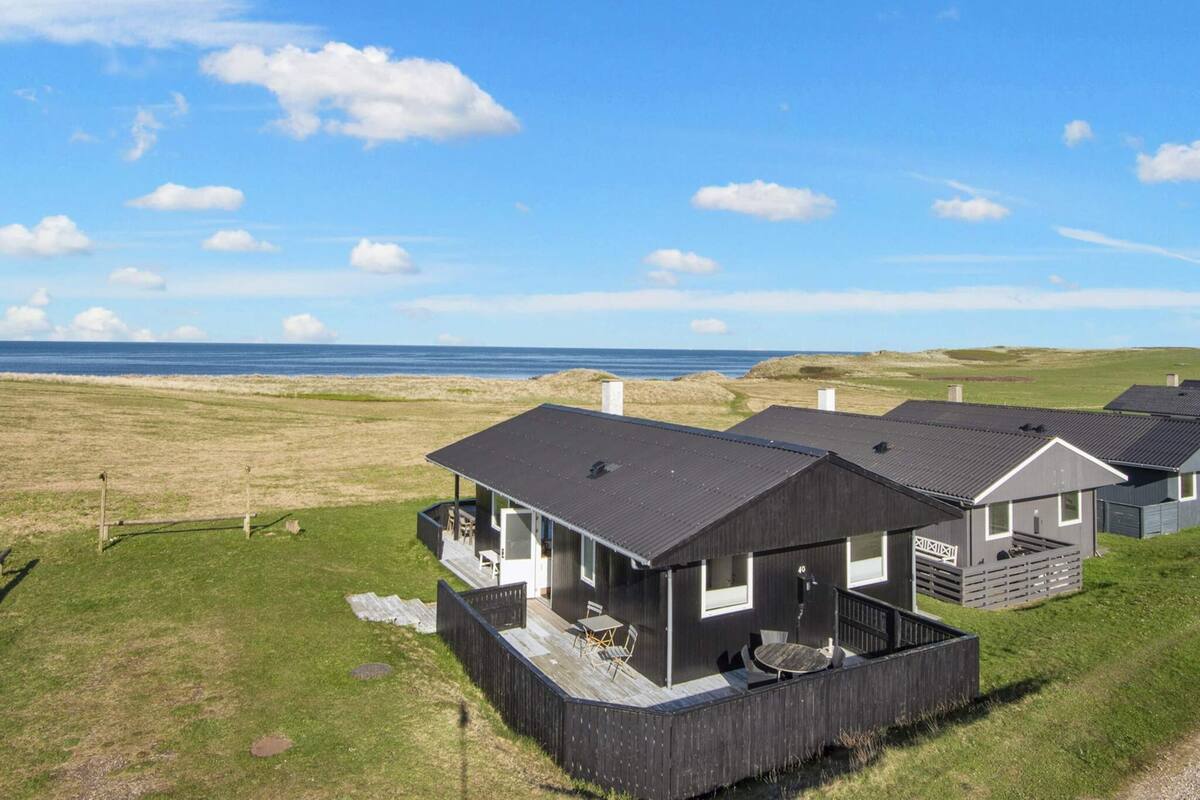 A row of modern cabins with a deck, a covered outdoor seating area, and a view of the sea.
