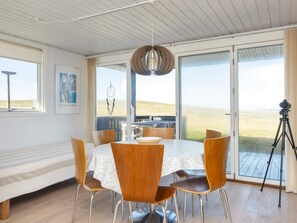 A dining area with a round table, wooden chairs, and a view through large glass doors to the outdoors. - 4 Star Holiday Home in Lemvig (Lemvig)