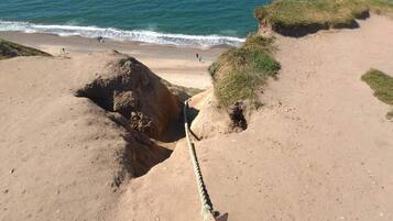 Una playa arenosa con una barrera de cuerda y un promontorio rocoso.