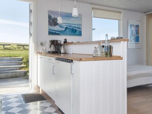 A kitchen with a wooden countertop, white cabinets, a coffee maker, and a view of the outdoors. - 4 Star Holiday Home in Lemvig (Lemvig)