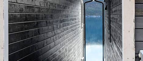 A wooden cabin with a view of a lake through a doorway.