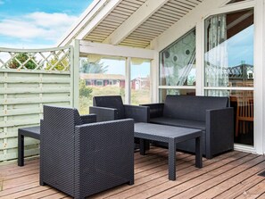 A covered outdoor seating area with wicker furniture and a wooden deck.