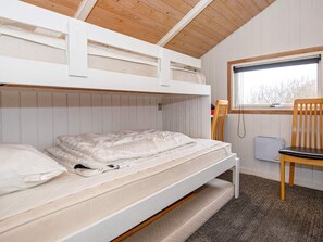 A bunk bed room with a window, a chair, and a radiator.