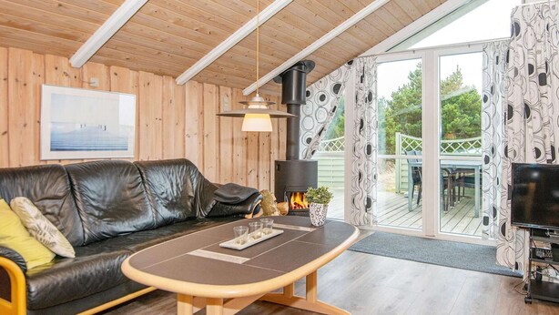 A cozy living room with a leather sofa, a wooden coffee table, a fireplace, and a TV. - 4 Star Holiday Home in Romo (Rømø)