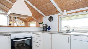 A modern kitchen with white cabinets, a Bosch dishwasher, a stove, and a clock on the wall. - 4 Star Holiday Home in Romo (Rømø)