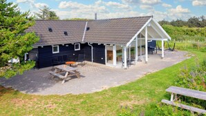 A black building with a sloped roof and a covered patio area with outdoor seating. - Luxury Retreat in Nr. Lyngby-by Traum (Lokken)