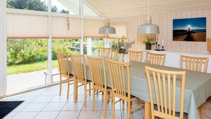 A dining area with a long table, wooden chairs, pendant lights, and a view of greenery outside. - Luxury Retreat in Nr. Lyngby-by Traum (Lokken)