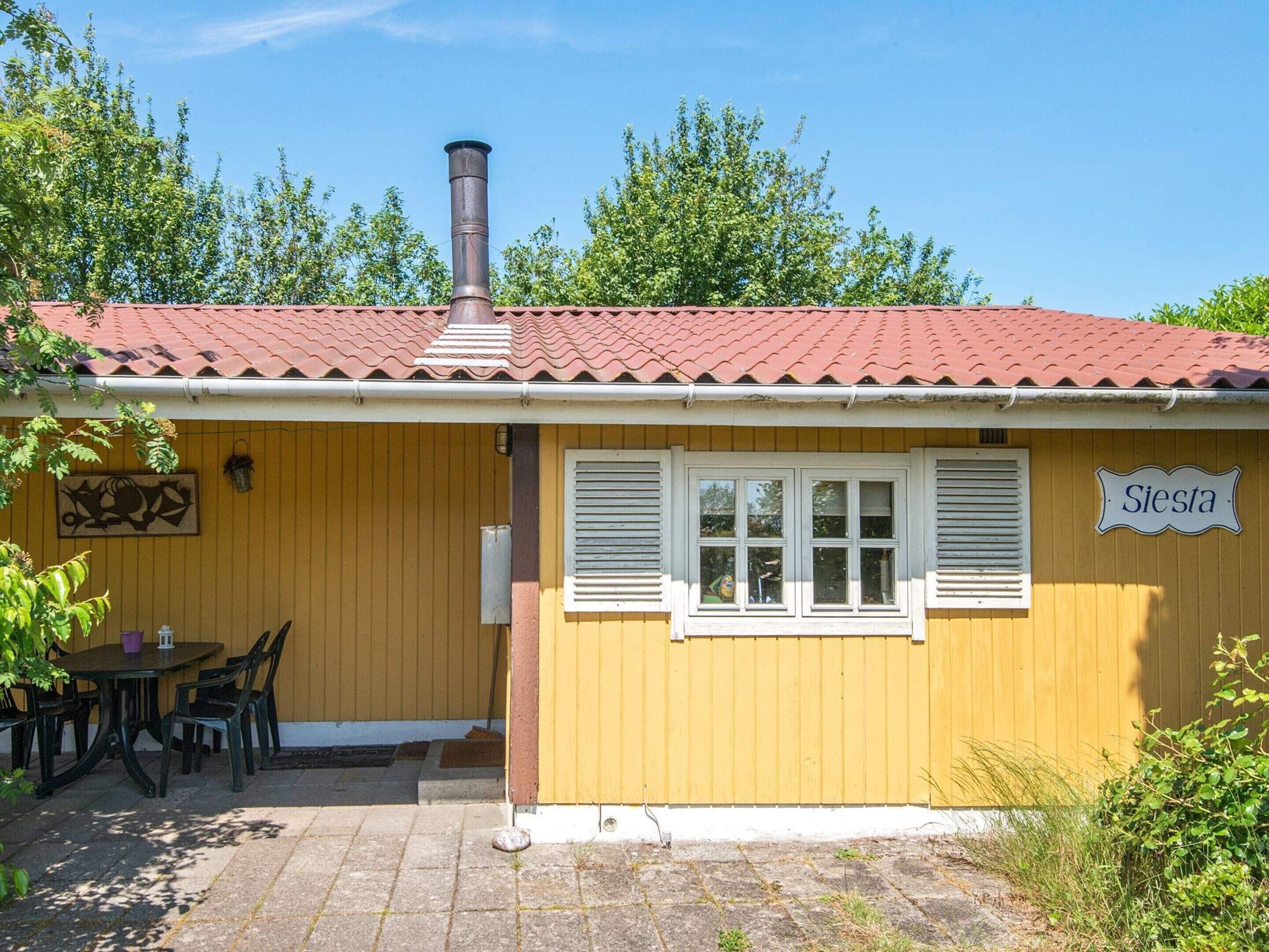 A yellow building with a red-tiled roof, a chimney, and a sign reading 'Siesta.'