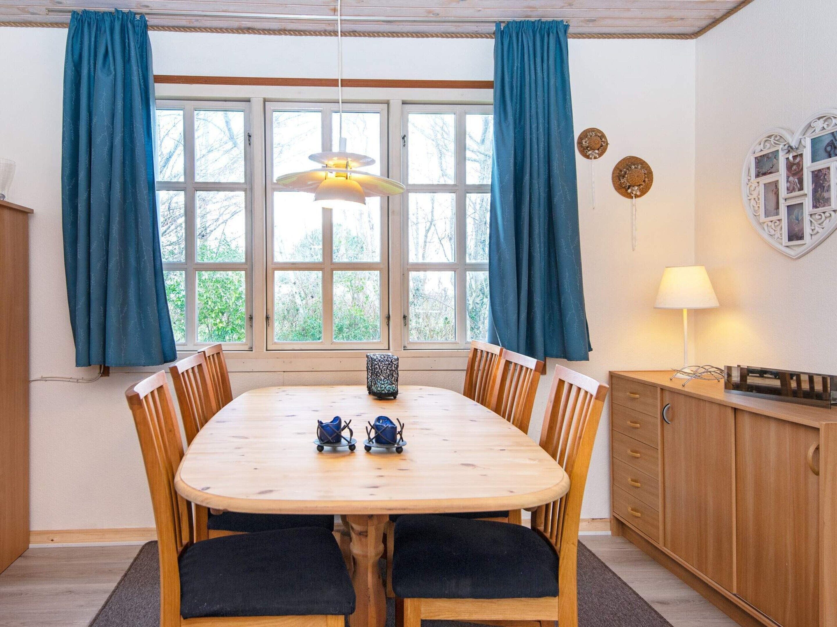 Een eetruimte met een houten tafel, stoelen en een hanglamp.