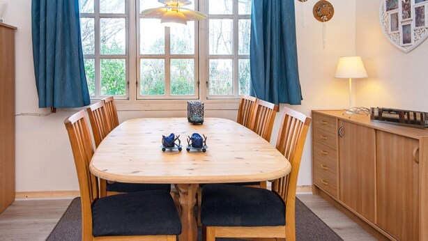 A dining area with a wooden table, chairs, and a hanging light fixture.