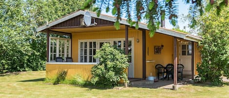 Eine Holzhütte mit Veranda, einem kleinen Tisch und Stühlen.