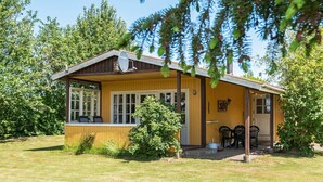 A wooden cabin with a porch, a small table, and chairs. - 4 Person Holiday Home in Nordborg (Nordborg)