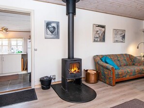 A cozy living room with a fireplace, a patterned sofa, and artwork on the wall. - 4 Person Holiday Home in Nordborg (Nordborg)