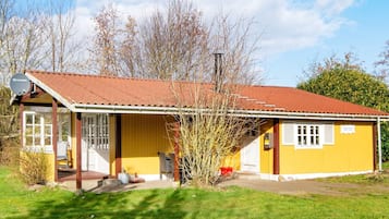 Um edifício amarelo com telhado vermelho, uma antena parabólica e uma placa com o texto 'Sicca'.