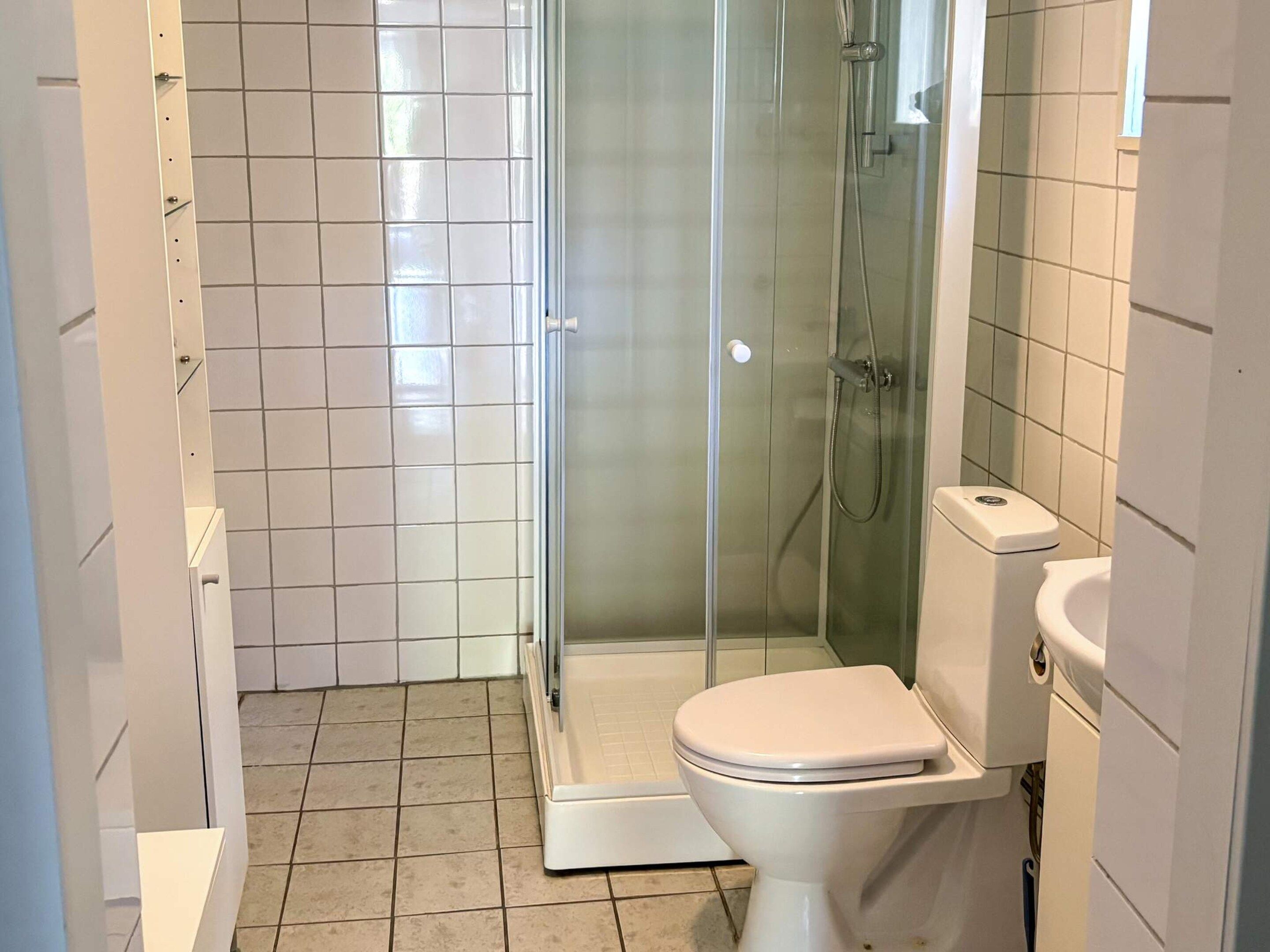 A bathroom with a glass shower enclosure, a white toilet, and a white sink.