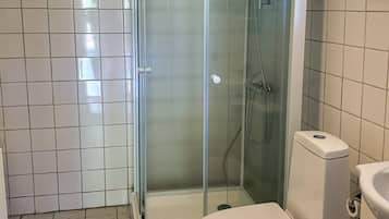 A bathroom with a toilet, a glass-enclosed shower, and tiled walls.
