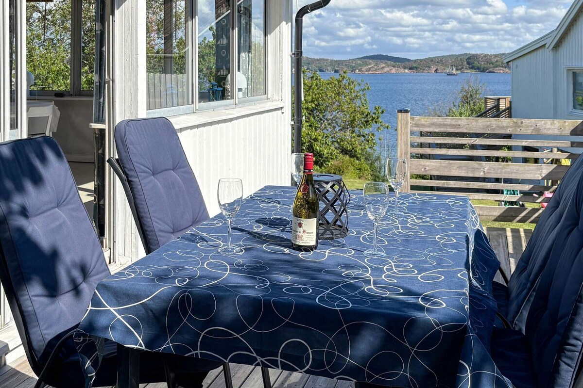 A table set outdoors with a bottle of wine, chairs, and a view of the sea.