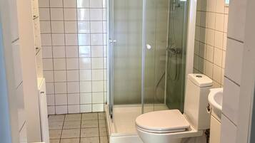 Une salle de bain avec une douche à parois de verre, des toilettes et un lavabo.