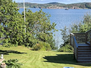 A deck overlooking a lake with a sailboat in the distance, surrounded by greenery. - 4 Star Holiday Home in Lysekil (Lysekil)