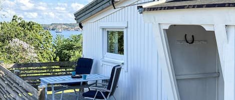 A deck with a table and chairs, a window, and a door with a horseshoe symbol.