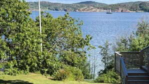 A deck overlooking a lake with a sailboat in the distance, surrounded by greenery. - 4 Star Holiday Home in Lysekil (Lysekil)