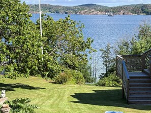 A deck overlooking a lake with a sailboat in the distance, surrounded by greenery. - 4 Star Holiday Home in Lysekil (Lysekil)
