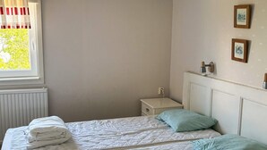 A bedroom with two beds, a radiator, a nightstand, and a window with curtains. - 4 Star Holiday Home in Lysekil (Lysekil)