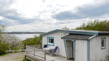 A small cabin with a porch, a table, and two chairs.