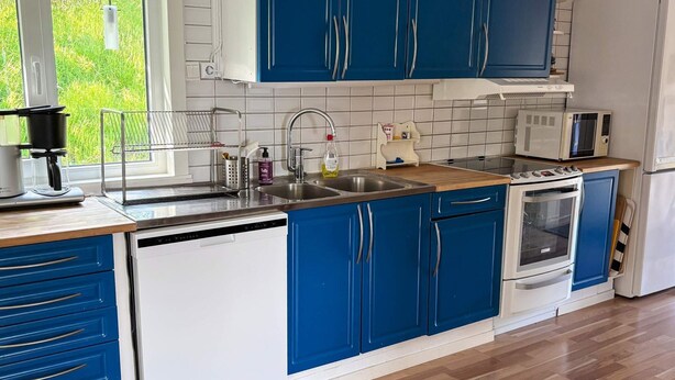 A modern kitchen with blue cabinets, a dishwasher, an oven, a microwave, and a refrigerator. - 4 Star Holiday Home in Lysekil (Lysekil)