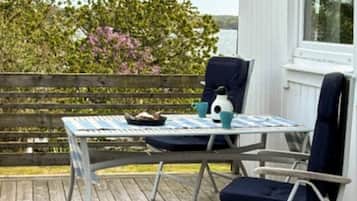 A wooden deck with a table and chairs, a bird feeder, and a view of the water.