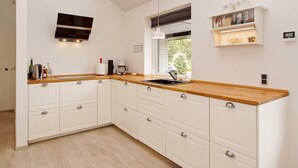 Eine moderne Küche mit weißen Schränken, einer Holz Arbeitsplatte und einem eingebauten Herd.