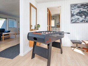 Relax in a warm and inviting space with a foosball table, comfortable seating, and a large abstract painting.