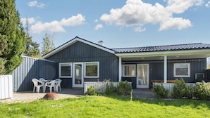 A two-story house with a covered patio, a fenced yard, and a small garden. - 6 Person Holiday Home in Ebeltoft (Ebeltoft)