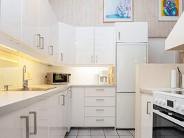 Una cocina moderna con armarios blancos, un microondas, una cafetera y una estufa.