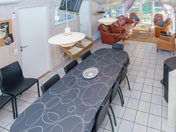 A dining area with a long table, chairs, and a sofa set.