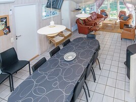 A dining area with a long table, chairs, and a sofa set.