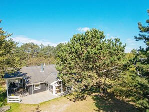A house with a deck, a covered patio, and a large tree in the yard. - 4 Star Holiday Home in Ebeltoft (Ebeltoft)