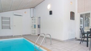 A swimming pool with a ladder, a door, and a table with chairs. - 4 Star Holiday Home in Ebeltoft (Ebeltoft)