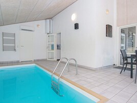 Una piscina con una escalera, una puerta y una mesa con sillas.