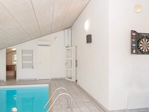 A swimming pool with a metal ladder, a door, and a dartboard on the wall.