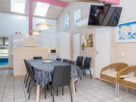 A dining area with a table, chairs, a television, and a wicker chair.