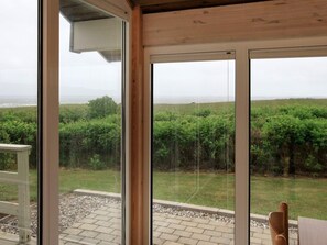 Una habitación con grandes puertas de cristal que dan a un jardín con vistas al mar.
