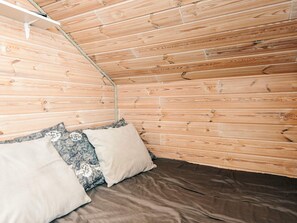 A room with wooden walls and a bed with a brown mattress and patterned pillows. - 4 Person Holiday Home in Hemmet (Hemmet)