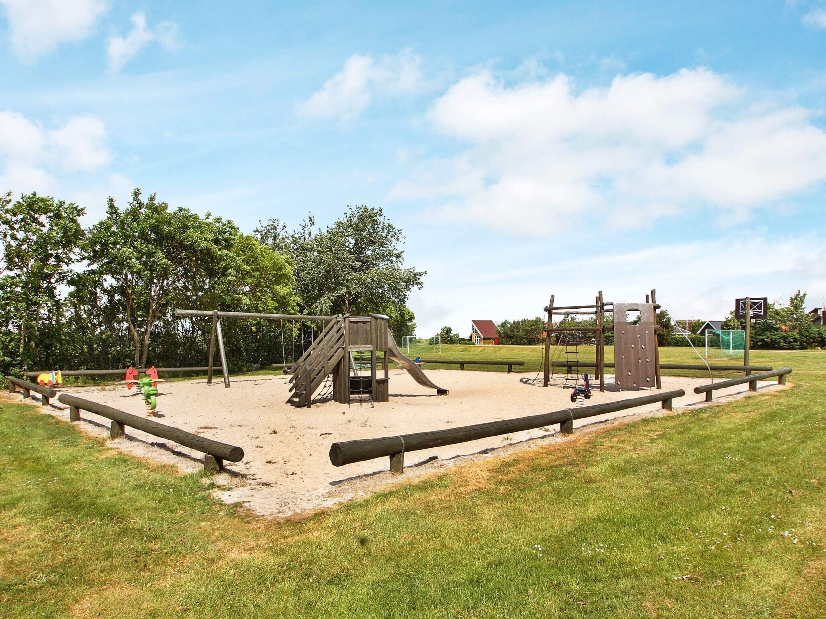 Un parque infantil con tobogán, columpios y estructura para escalar.
