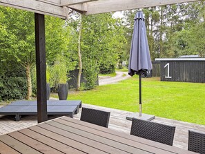 An outdoor patio with a table and chairs, a potted plant, and a shed in the background. - 4 Star Holiday Home in Hadsund (Hadsund)